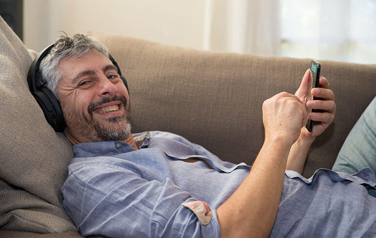 homme sourire barbe divan écouteur 