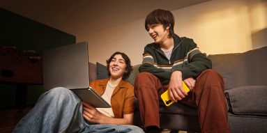 Two teenagers are looking at a laptop
